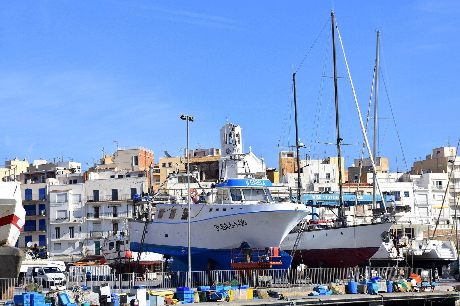 Fishing boat in dry dock beside the harbor buildings of L’Ametlla de Mar