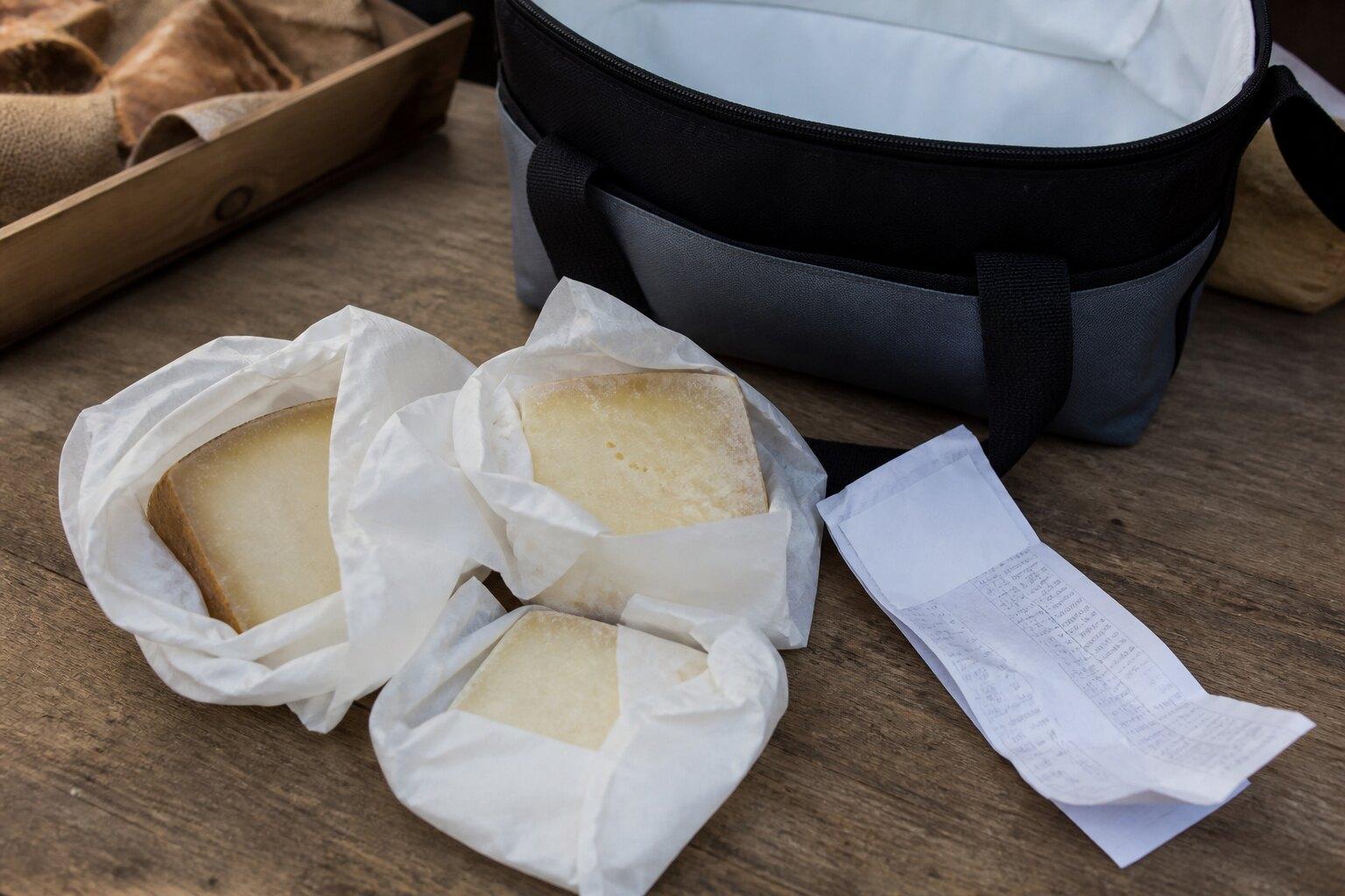 Wrapped cheese portions beside a market receipt and cooler bag
